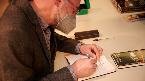Ein Mann signiert ein Buch.  Foto: Moritz Küstner