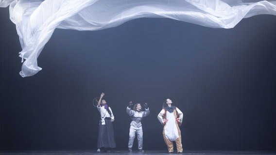 Drei Frauen stehen nebeneinander auf einer Theaterbühne. Über ihnen schwebt ein weißes Tuch. © Sinje Hasheider Foto: Sinje Hasheider