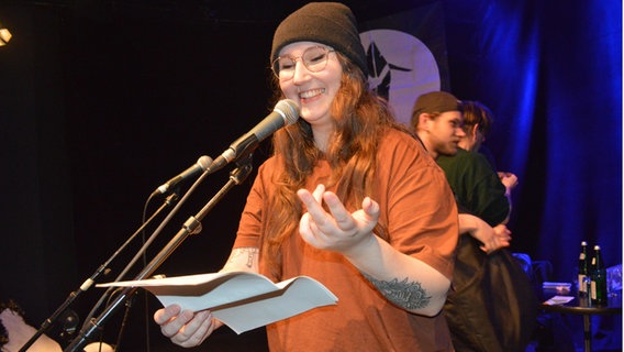 Die Poetry Slammerin Selina Seemann steht im Statt-Café Kiel am Mikrofon und spricht. © NDR Foto: Anne Passow