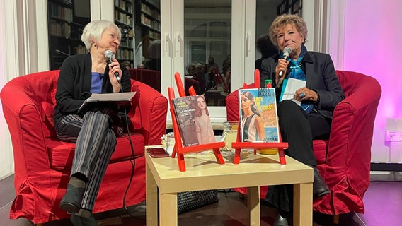 Dacia Maraini und Dr. Paola Barbon sitzen auf zwei roten Sesseln im Italienischen Kulturinstitut in Hamburg. Dr. Barbon übernimmt die Moderation und Übersetzung ins Deutsche bei der Lesung mit Diskussion. © NDR 
