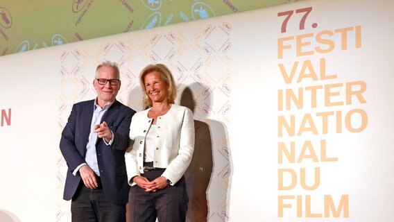 Iris Knobloch (r), Präsidentin des Filmfestivals von Cannes, und Thierry Fremaux, Leiter des Filmfestivals von Cannes, stehen vor einer Wand nach der Bekanntgabe des Programms des Internationalen Filmfestivals von Cannes für die kommende 77. Ausgabe der Filmfestspiele. © Aurelien Morissard/AP/dpa +++ dpa-Bildfunk + Foto: Aurelien Morissard