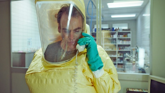 Filmszene mit Sebastian Blomberg als Biowaffenexperte im gelben Schutzanzug, Szene aus Johannes Nabers Film "Curveball © Sten Mende 