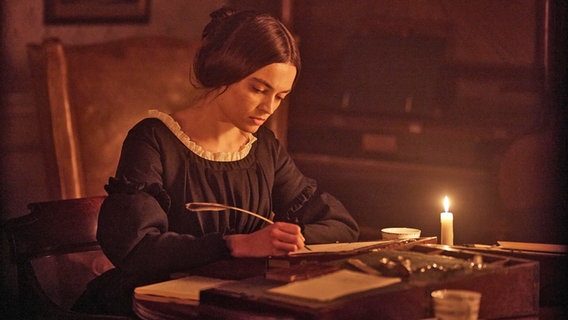 Die Brontë-Schwester Emily schreibt bei Kerzenlicht - Szene aus dem Kinofilm "Emily" © Wild Bunch Germany, 2022 