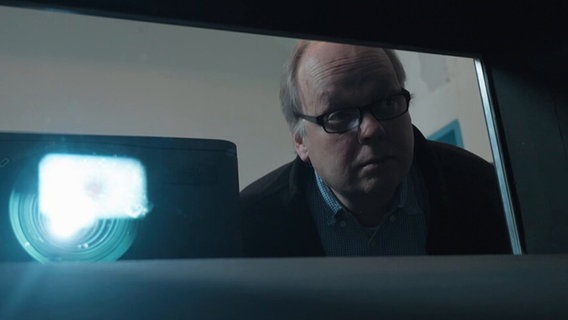 Filmvorführer Eckhard Pabst schaut durch ein kleines Fenster © NDR.de 