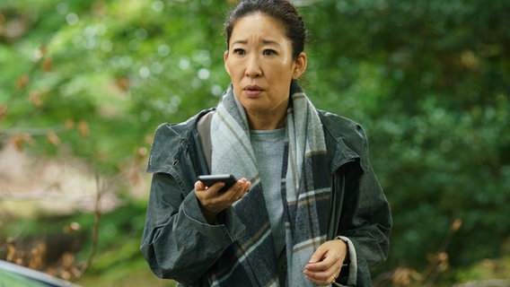 Eve (Sandra Oh) steht mit einem Handy in der Hand - Szene aus "Killing Eve" (BBC-Serie im ZDF) © ZDF und Nick Briggs. Foto: ZDF und Nick Briggs.