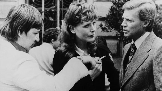 Schwarz-weiß-Foto aus dem Jahr 1974 mit einer Szene vom Dreh des Films "Martha" mit drei diskutierenden Personen (Rainer Werner Fassbinder, Margit Carstensen und Karlheinz Bohm,) Schwarz-weiß-Foto aus dem Jahr 1974 mit einer Szene vom Dreh des Films "Martha" mit drei diskutierenden Personen (Rainer Werner Fassbinder, Margit Carstensen und Karlheinz Bohm,) © picture alliance / Everett Collection