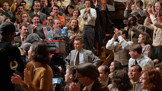 Cillian Murphy als Robert Oppenheimer bei einem Fernsehauftritt vor Publikum -  Szene aus "Oppenheimer" von Christopher Nolan © Universal Pictures 