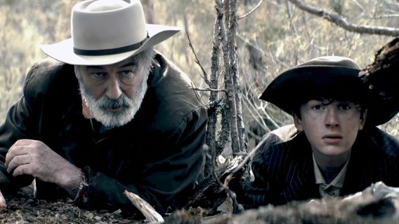 Szene aus dem Film "Rust - Legende des Westens": Ein älterer Mann und ein Junge liegen auf der Lauer. © 2025 RUST MOVIE PRODUCTIONS LLC, ALL RIGHTS RESERVED 