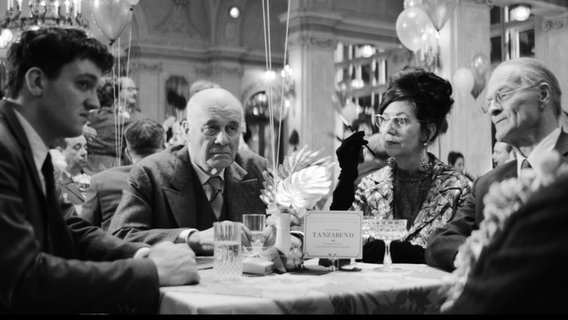 Menschen an einem Tisch in Outfits der 60er-Jahre - Szene aus dem Film "Die Theorie von allem" von Timm Kröger © Neue Visionen Filmverleih 