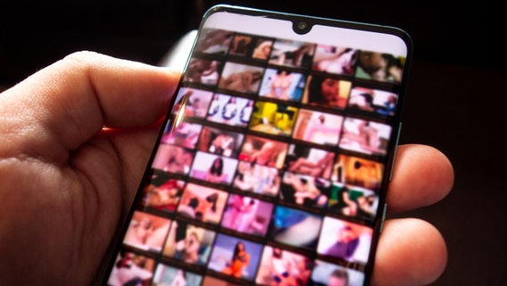 Pornografische Bilder sind verschwommen auf dem Bildschirm eines Smartphones zu sehen. © picture alliance Foto: Andreas Franke