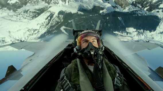Schauspieler Tom Cruise schaut über Kopf aus seinem Flugzeug auf Berge - Szene aus "Top Gun Maverick" © Paramount 