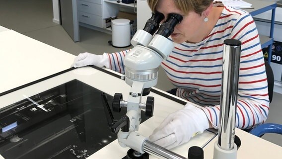 Eine Frau untersucht mithilfe eines Stereoskops einen Silbergelatineabzug. © Sprengel Museum Foto: C. Kamrath