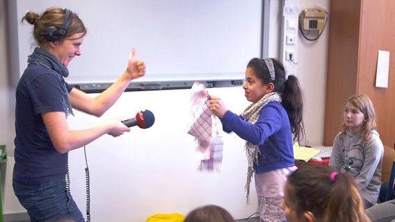 Jantje Fischhold vom NDR Projekt "Hörspiel in der Schule" macht mit einer Schülerin der Elbschule und einem Geschirrtuch Fledermausgeräusche. © NDR 