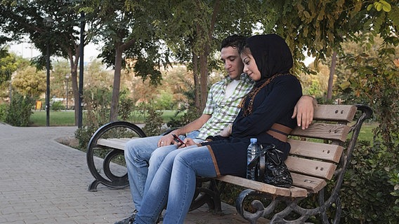 Ein islamisches Paar sitzt auf einer Parkbank. © Imago 