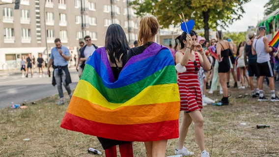 Zwei Frauen tragen eine Regenbogenflagge um die Schultern © IMAGO/Virginia Garfunkel 