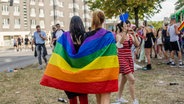 Zwei Frauen tragen eine Regenbogenflagge um die Schultern © IMAGO/Virginia Garfunkel 