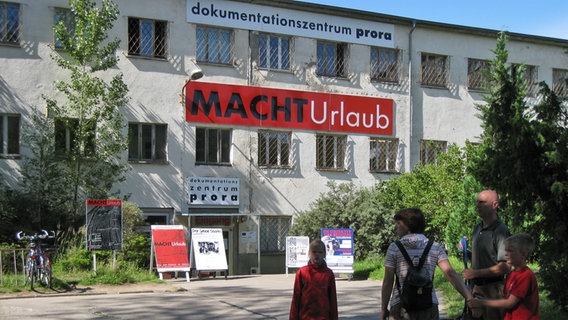 Eine Familie steht vor dem Eingang des Dokumentationszentrums Prora. Eine Familie steht vor dem Eingang des Dokumentationszentrums Prora. © NDR Foto: Johann Lühe