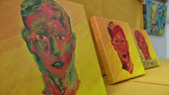 Ein paar Ölgemälde von Gesichtern auf gelbem Grund. © NDR Foto: Lina Bande