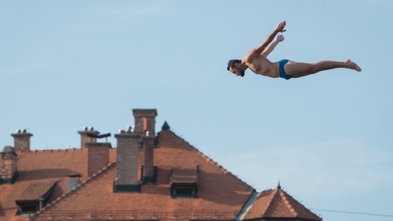 Ein Turmspringer springt in Maribor von einer Brücke ins Wasser. © picture alliance/ZUMA Press Foto: Milos Vujinovic