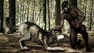 Ein Steinzeitmensch hält einen Wolf am Kopf. © picture alliance | Knut Niehus 