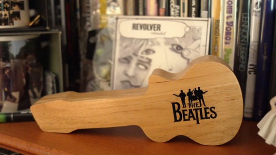 Eine gitarrenförmige Holzfigur, auf der "The Beatles" steht © Screenshot NDR 