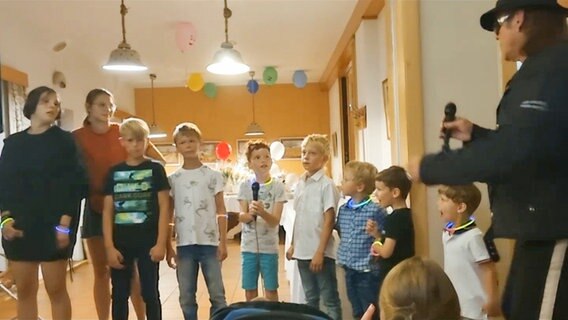 Eine erwachsene Person singt zusammen mit neun Kindern und Jugendlichen © NDR 