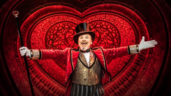 Musicaldarsteller Gavin Tumbull im Musical "Moulin Rouge" in Köln mit rotem Frack und Zylinder © Johann Persson Foto: Johann Persson