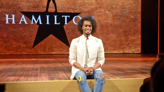Musical-Darsteller Benét Monteiro sitzt auf der Bühne von "Hamilton" in Hamburg beim Pressetermin © NDR Foto: Patricia Batlle