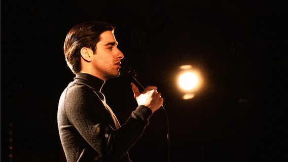 Der Sänger Atrin Madani singt in ein Mikrofon. © Atrin Madani 