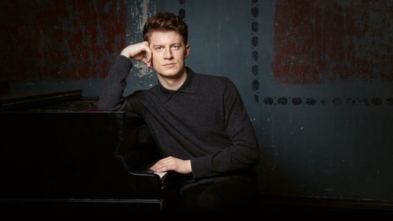 Alexander Krichel lehnt an einem Flügel © Sony Classical Foto: Raimar von Wienskowski