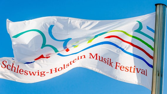 Eine Fahne mit dem Logo des Schleswig-Holstein Musikfestivals weht im Wind. © dpa Foto:  Markus Scholz