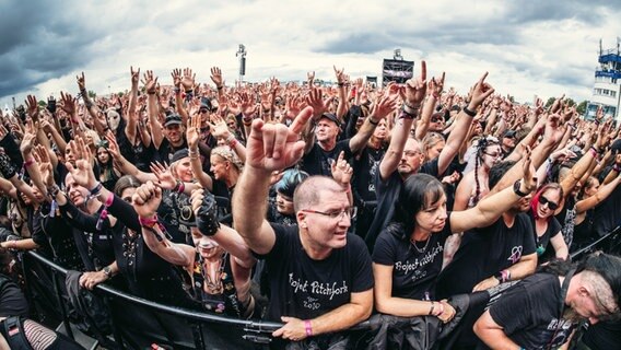 Fans heben die Hände im Konzert beim M'era Luna Gothic-Festival vor zahlreichen Besuchern. © NDR Foto: Benjamin Hüllenkremer