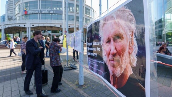 Menschen betrachten ein Plakat von Musiklegende Roger Waters © dpa Foto: Andreas Arnold
