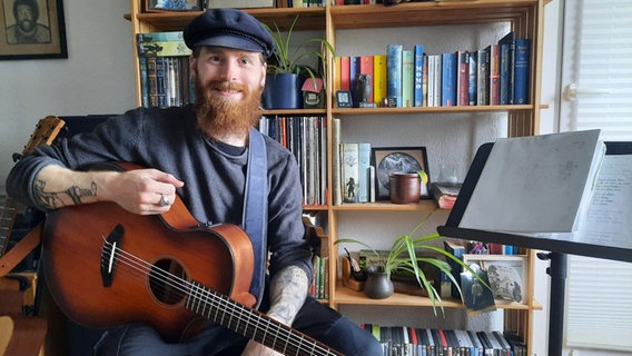 Liedermacher Lennon von Seht hält eine Gitarre in der Hand und lächelt in die Kamera. © NDR Foto: Lina Bande