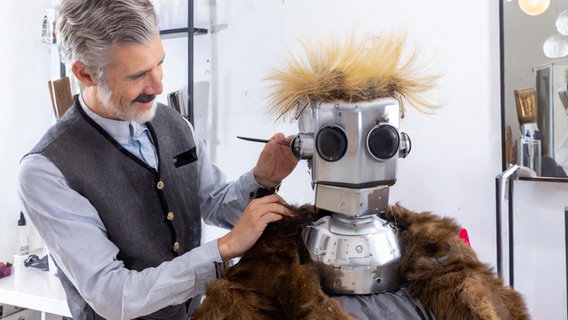 Pepper snackt Platt: Ein Roboter sitzt beim Friseur © NDR Foto: Prompter Lornz Lorenzen