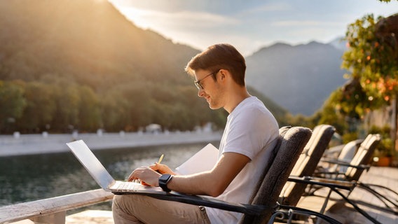 Ein junger Mann sitzt draussen am Laptop in der Sonne. © NDR/Lornz Lorenzen Foto: Prompt / Lornz Lorenzen Adobe Firefly 2