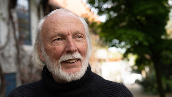 Rainer Pruess steht auf einem Hinterhof und lächelt in die Kamera. © NDR Foto: Lornz Lorenzen