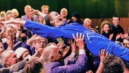 Die Schauspielerin Pauline Rénevier lässt sich vom Publikum auf Händen ein Mal in die Saalmitte und zurück zur Bühne tragen. © picture alliance/dpa | Markus Scholz 