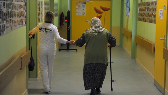 Eine Pflegerin begleitet eine ältere Frau auf ihr Zimmer © picture alliance / dpa Foto: Soeren Stache