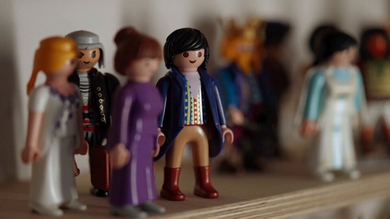 Mehrere Playmobil-Figuren stehen in einem Regal © Screenshot NDR 