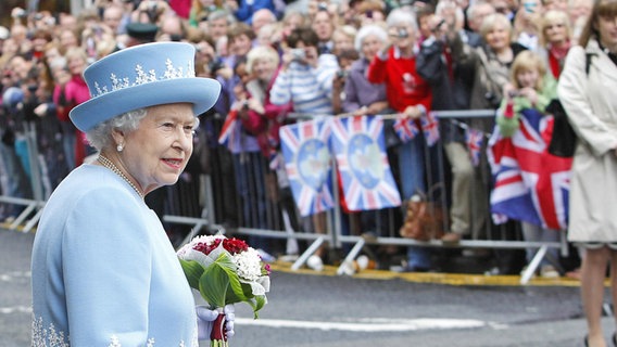 Die englische Queen Elizabeth im blauen Kleid und Hut vor jubelnden Menschen © Julien Behal/Press Association/dpa +++ dpa-Bildfunk Foto: Julien Behal