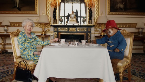 Königin Elisabeth II. trinkt Tee mit dem Bären Paddington. © picture alliance / Photoshot 