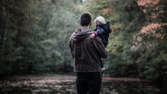 Ein junger Vater hält sein Kind auf den Armen. © David-W- / photocase.de Foto: David-W-