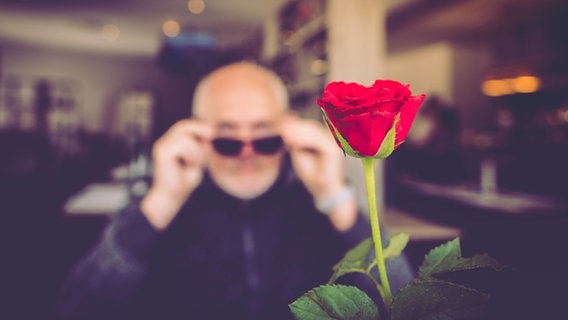 Rote Rose für einen Mann mit Sonnenbrille - im Restaurant. © Constanze Leidel / photocase.de Foto: Constanze Leidel