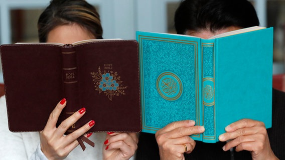 Eine Frau liest aus dem Koran, daneben liest ein Mann aus der Bibel © picture alliance / Godong Foto: Pascal Deloche
