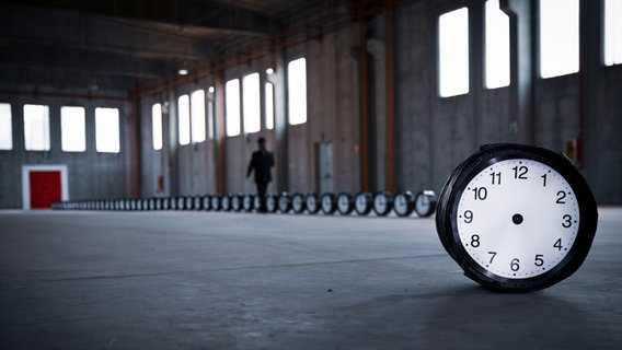 Eine Reihe von Uhren steht in einem leeren Fabrikgebäude. Eine zeigerlose Uhr ist frontal zu sehen. Eine Reihe von Uhren steht in einem leeren Fabrikgebäude. Eine zeigerlose Uhr ist frontal zu sehen. © Roberto Agagliate / photocase.de Foto: Roberto Agagliate