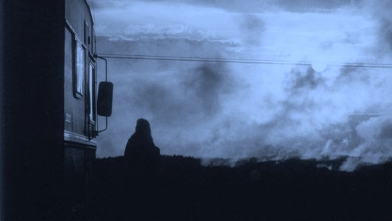 Die Silhouette einer Person steht bei wolkigem Himmel vor einem Wohnwagen © photocase / k a t i n k a Foto: k a t i n k a