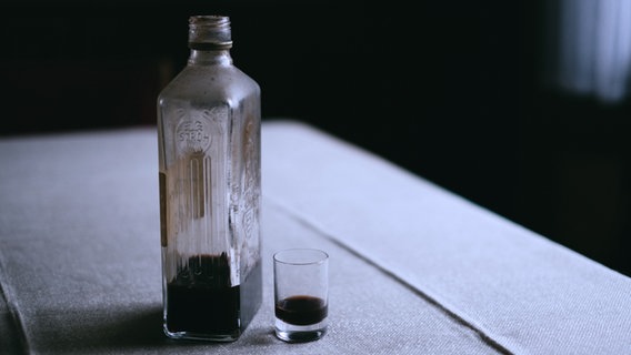 Eine Schnapsflasche und ein Glas stehen auf einem Tisch. © photocase / Eliza Foto: Eliza