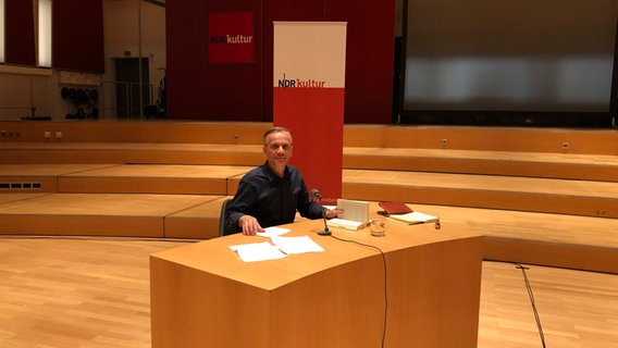 Lutz Seiler sitzt an einem Tisch auf der Bühne des Rolf-Liebermann-Studios. © NDR Foto: Birgit Laabs