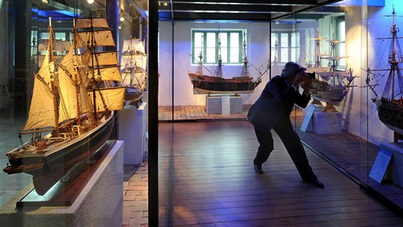 Ein Besucher fotografiert historische Segelschiffe im Sielhafenmuseum in Carolinensiel © dpa - Report Foto: Ingo Wagner